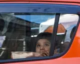 Niño mira por la ventana del coche, apoyado en el cristal, sin silla en el coche. Reflejos en el vidrio.