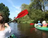 Spływ kajakowy po lubelskiej rzece. Wiosłowanie w zielonym kajaku, w tle inni kajakarze.