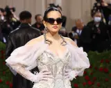Rosalía deslumbrante en la Met Gala, con un vestido blanco adornado y gafas de sol vanguardistas.