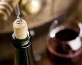 Korek wyjmowany z butelki, kieliszek wina i beczka. Czy wino ma datę ważności? To pytanie zadaje sobie wielu miłośników tego trunku.