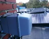 System podgrzewania paneli fotowoltaicznych zamontowany na dachu, obok ceglanej ściany.
