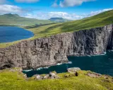 Scogliere imponenti e un lago blu intenso nelle Isole Faroe, dove gli abitanti vivono in armonia con la natura selvaggia.