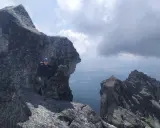 Wspinacz w kasku na skalistym szczycie, podziwiający widok. Tatry poza szlakiem, gdzie każdy krok to przygoda.
