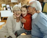 Abuelos riendo y abrazando a su nieta. Un momento tierno que demuestra la alegría de los padres que dejan a sus hijos con los abuelos.