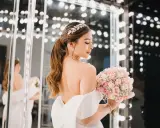 Novia con peinados de novia recogidos elegantes, tiara brillante y ramo de rosas.