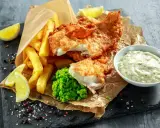 Poisson pané croustillant, frites dorées, purée de petits pois et une sauce tartare crémeuse pour accompagner ce plat de fish and chips.