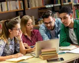 Studenci pochłonięci nauką historii przy laptopie w bibliotece.