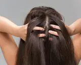 Une femme se touche les cheveux, montrant comment hydrater son cuir chevelu pour des cheveux sains et brillants.