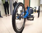 Niebieski prototyp roweru trójkołowego z dużym tylnym kołem i siedzeniem.