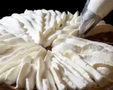 Garniture d'une tarte avec une poche à douille, évoquant la recette crémeux vanille Michalak.