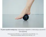 Rolowanie stopy na małej, czarnej piłeczce z niebieskimi kropkami. Pomaga rozluźnić mięśnie.