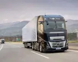 Camión Volvo FH Aero 780 negro con remolque blanco avanza por una carretera montañosa.