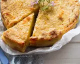 Delizioso gateau di patate dorato e croccante, guarnito con rosmarino fresco. Una fetta è già stata servita.