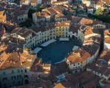 Vista aerea di Piazza dell'Anfiteatro a Lucca, perfetta per un weekend indimenticabile tra tetti rossi e vita cittadina.