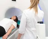 Patient liegt auf dem Tisch für die pelottierung des duralschlauches. Eine Ärztin in weißem Kittel überwacht den Vorgang.