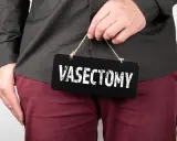 Mężczyzna trzyma tabliczkę z napisem "VASECTOMY". Czy po wazektomii można mieć dzieci? To pytanie nurtuje wielu.