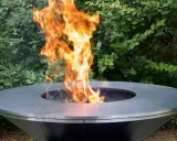 Un moderno braciere da giardino, con fiamme vivaci che danzano al centro, crea un'atmosfera accogliente.