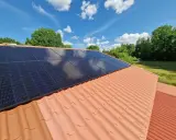 Solceller på ett tegeltak, redo för besiktning. Solen skiner på de mörka panelerna mot en blå himmel med vita moln.