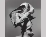 Modella con un abito plissettato bianco, un'opera d'arte di Irving Penn, che nasconde il viso tranne un occhio penetrante.