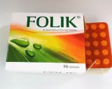 Opakowanie leku Folik z kwasem folowym, obok którego leży pomarańczowa folia z 90 tabletkami.