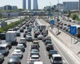 Congestión vehicular en una autopista, reflejo de la movilidad urbana. Coches y camiones detenidos en múltiples carriles bajo un cielo despejado.
