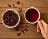 Miseczka suszonego hibiskusa i kubek czerwonego naparu. To jakby hibiskus w ciąży, gotowy do rozkwitu w aromatycznym napoju.