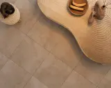 Kot śpi na pufie, obok falistego stolika z bananami i wazonami. Podłoga z gres lappato czyszczenie jest nieskazitelna.