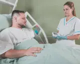 Pielęgniarka bada pacjenta w szpitalu. Walka z rakiem i nowotworem wymaga wsparcia medycznego.