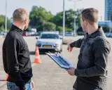 Instruktor omawia z kursantem plan trasy, świętując jego pozytywny wynik egzaminu teoretycznego.
