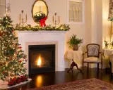 Ideas para decorar una chimenea navideña: árbol iluminado, guirnaldas verdes, un tren de juguete y un fuego acogedor.