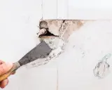 Mano con espátula preparando una pared para tapar agujeros.