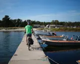 En cyklist på en brygga med båtar vid en svensk kust. Perfekt för att utforska cykelleder Sverige.