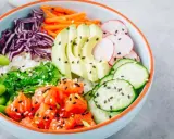 Eine bunte Poke Bowl mit Lachs, Avocado, Edamame, Rotkohl, Gurke, Radieschen und Seetang.