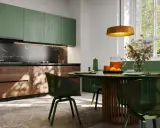 Elegancka kuchnia art deco z zielonymi frontami, drewnianymi detalami i marmurowym blatem. Okrągły stół z zielonymi krzesłami zaprasza do wspólnych posiłków.