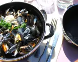 Moules marinières crémeuses, une spécialité culinaire normandie, servies dans une cocotte avec du pain frais.