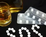 Szklanka alkoholu i blistry z tabletkami układają się w napis SOS. Czy to pytanie o benzodiazepiny, co to jest i jakie ryzyko niesie ich połączenie z alkoholem?