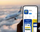Aplikacja Ryanair na telefonie, pokazująca jak udostępnić kartę pokładową. W tle samolot lecący nad chmurami.