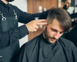 Fryzjer dopracowuje męskie fryzury z grzywką do przodu, tworząc stylowy look.