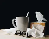 Kubek z herbatą, chusteczki i okulary. Urlop L4 nie zawsze jest wypoczynkiem.