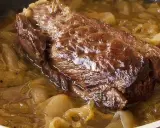 Une succulente buche d'onglet mijote dans une sauce aux oignons caramélisés, prête à être dégustée.