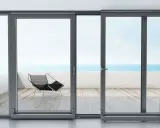 Ventanas osciloparalelas con vista al mar. Un sillón moderno en la terraza de madera.