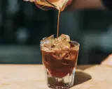 Ein Espresso fließt in ein Glas mit Eiswürfeln. Ist kalter Kaffee gesund? Diese Erfrischung könnte eine Antwort sein.