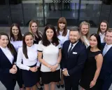 Grupa prawników w garniturach i strojach biznesowych pozuje przed budynkiem.