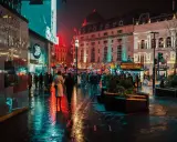 Luci al neon e riflessi sull'asfalto bagnato, la vibrante vita notturna londra pulsa tra la folla e gli edifici storici illuminati.