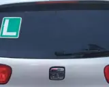 El coche tiene una L verde en la ventana trasera, indicando que el conductor está aprendiendo.