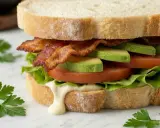 Ein BLT-Sandwich mit knusprigem Speck, saftigen Tomaten, cremigem Avocado und knackigem Salat auf getoastetem Brot.