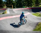 Chłopiec na rowerze pokonuje zakręty na pumptracku, ciesząc się jazdą po falistym torze.