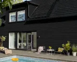 Ett modernt svart hus med pool och uteplats. Perfekt för att måla i solsken och njuta av sommaren.