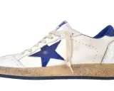 Białe sneakersy z niebieską gwiazdką, znane jako buty z gwiazdką, mają przetarty wygląd i niebieskie detale.