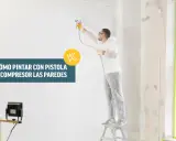 Hombre con traje protector pintando una pared con pistola y compresor.